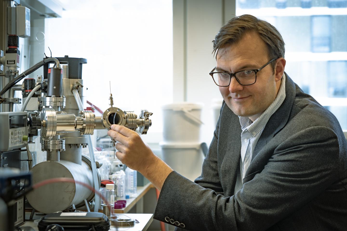 Professor Kasper Moth-Poulsen holding a tube containing the catalyst in front of the ultra-high vacuum setup that was used to measure the heat release gradient in the molecular solar thermal energy storage system. Source: Johan Bodell/Chalmers University of Technology
